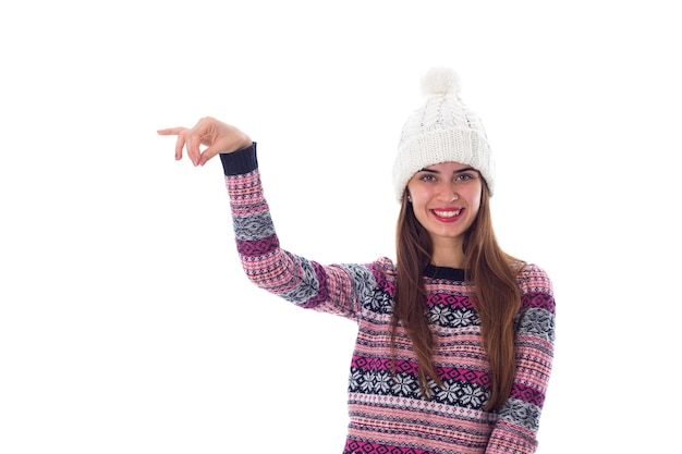 Giovane donna sorridente con cappello bianco e maglione viola che tiene qualcosa su sfondo bianco in studio