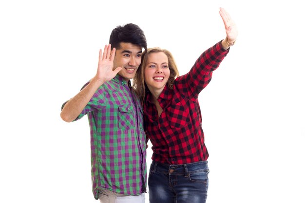 Giovane donna sorridente con lunghi capelli castani e giovane bell'uomo con capelli scuri in camicie a quadri e jeans che sventolano su sfondo bianco in studio