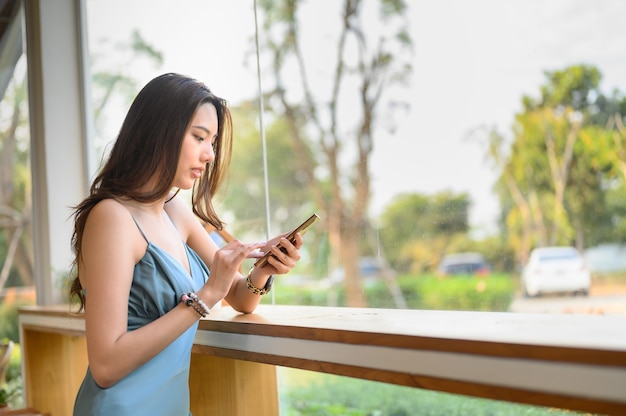 Giovane donna sorridente con mano felice premendo lo smartphone