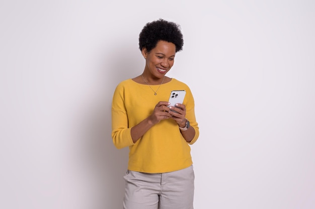 Giovane donna sorridente con messaggi di testo capelli corti afro su smart phone