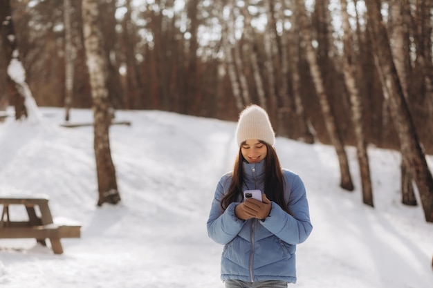 Giovane donna sorridente con smart phone e paesaggio invernale