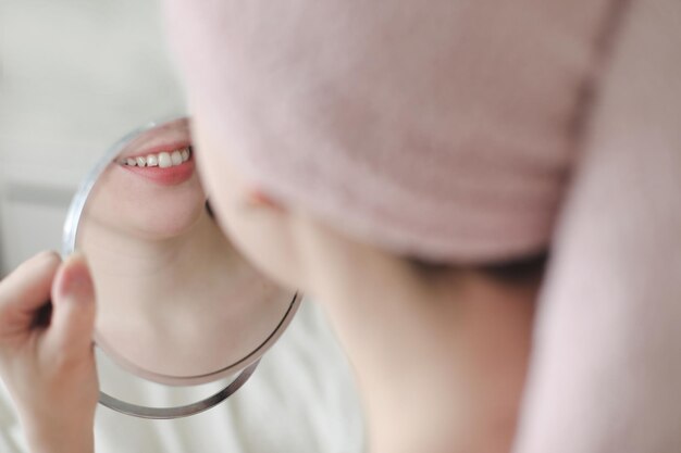 giovane donna sorridente con un asciugamano sulla testa guardandosi allo specchio