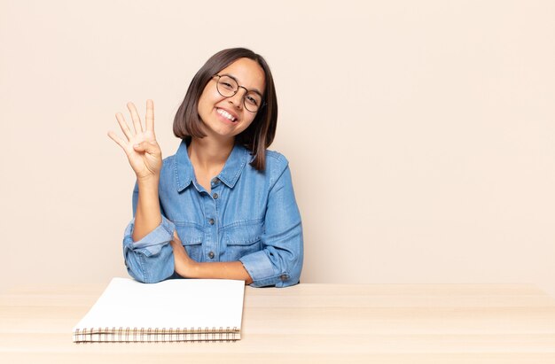 Giovane donna sorridente e dall'aspetto amichevole, mostrando il numero quattro o quarto con la mano in avanti