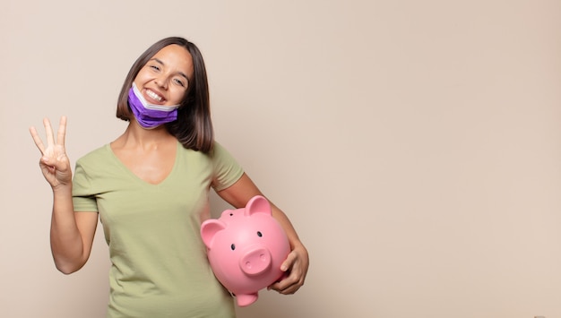 Giovane donna sorridente e dall'aspetto amichevole, mostrando il numero tre o il terzo con la mano in avanti, conto alla rovescia