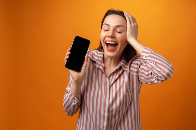 Giovane donna sorridente felice che ti mostra lo schermo nero dello smartphone con lo spazio della copia