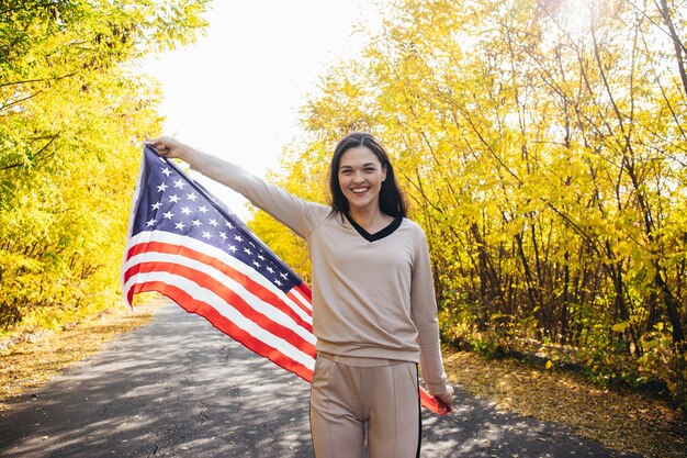 Giovane donna sorridente felice con la bandiera americana