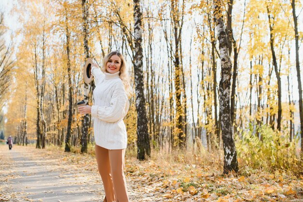 Giovane donna sorridente felice nel parco il giorno di autunno