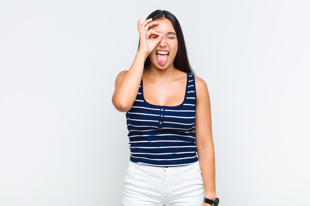 Giovane donna sorridente felicemente con faccia buffa, scherzando e guardando attraverso lo spioncino, spiando i segreti