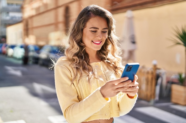 Giovane donna sorridente fiducioso utilizzando lo smartphone in strada