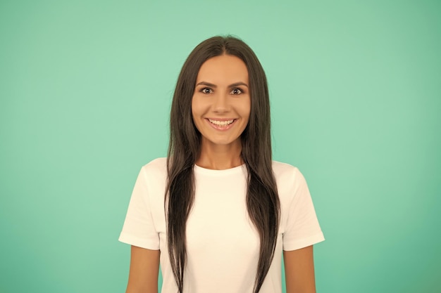 Giovane donna sorridente in camicia bianca su sfondo blu