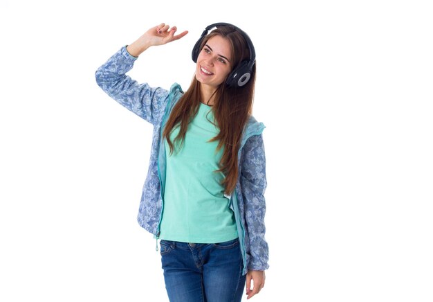 Giovane donna sorridente in camicia blu che ascolta la musica in cuffie nere in studio