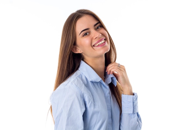 Giovane donna sorridente in camicia blu che tiene il colletto su sfondo bianco in studio