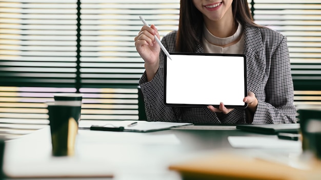 Giovane donna sorridente in giacca e cravatta che tiene lo schermo vuoto della tavoletta digitale per il tuo testo pubblicitario