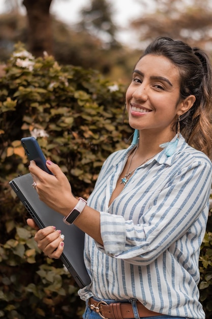 Giovane donna sorridente mentre controlla il suo smartphone lasciando l'università