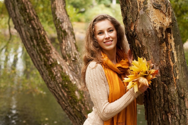 Giovane donna sorridente nel parco di autunno, fine su