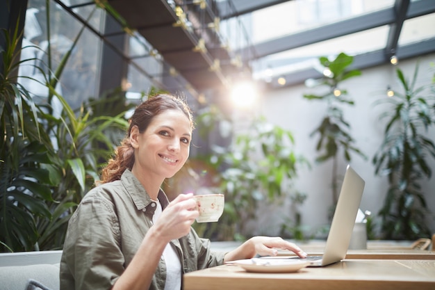 Giovane donna sorridente nel terrazzo soleggiato del caffè