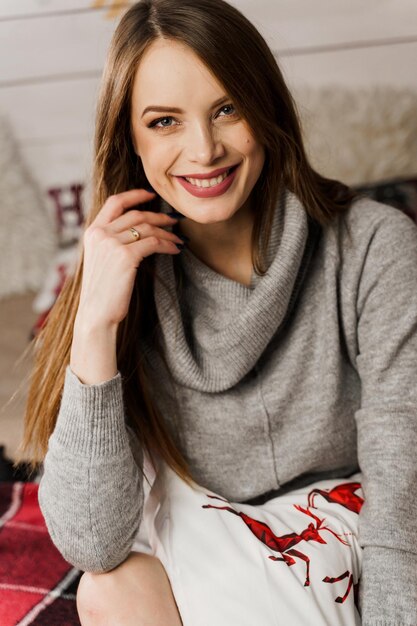 Giovane donna sorridente nella decorazione del nuovo anno. Celebrazione di Natale. Attraente ragazza indossata in caldo maglione di lana e calzini.