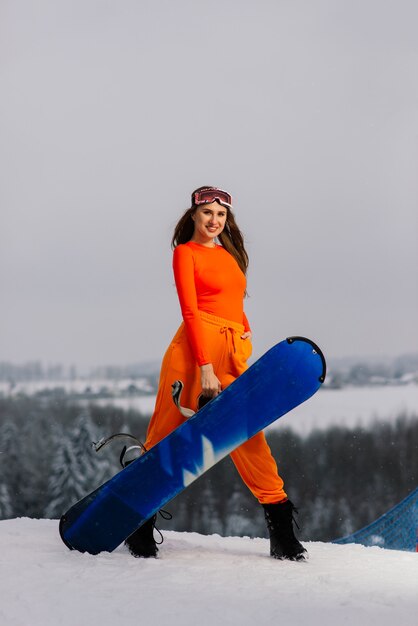 Giovane donna sorridente sportiva in inverno con snowboard, occhiali