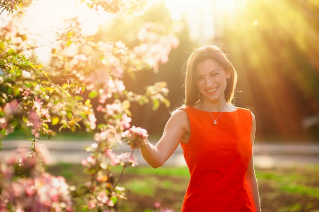 Giovane donna sorridente sul campo di alberi di fioritura della molla