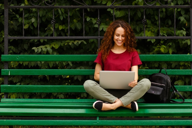 Giovane donna sorridente utilizzando il suo computer portatile nel parco