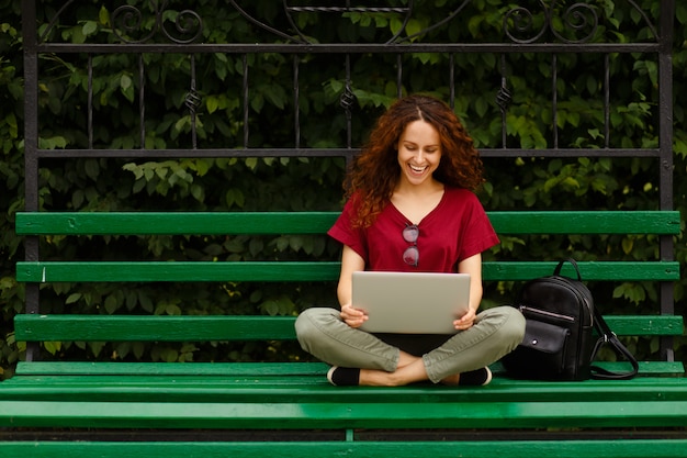 Giovane donna sorridente utilizzando il suo computer portatile nel parco