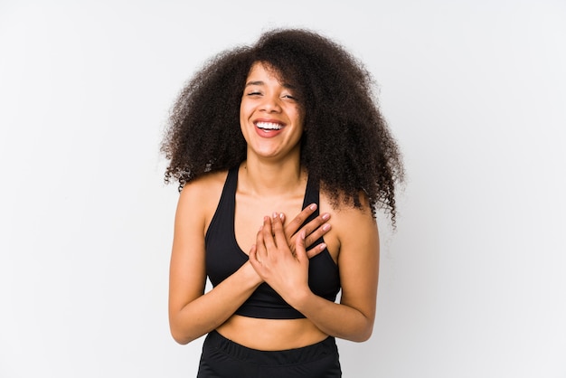 Giovane donna sportiva afroamericana che ride tenendo le mani sul cuore