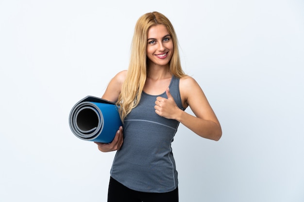 Giovane donna sportiva andando a lezioni di yoga mentre si tiene una stuoia isolata