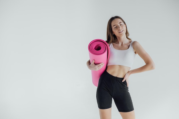 Giovane donna sportiva che fa pratica di yoga isolata su fondo bianco. Concetto di vita sana