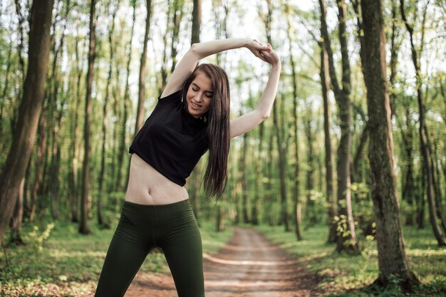 Giovane donna sportiva che funziona nella foresta