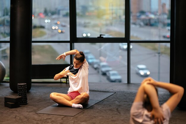 Giovane donna sportiva che pratica yoga lavorando indossando abbigliamento sportivo