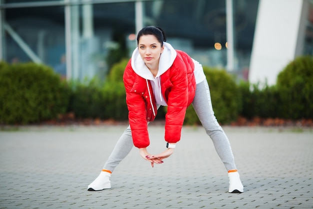 Giovane donna sportiva che si estende nella città moderna