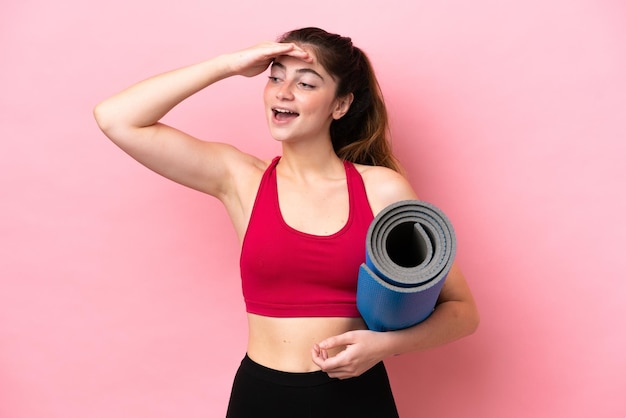 Giovane donna sportiva che va a lezioni di yoga mentre si tiene un tappetino sorridendo molto