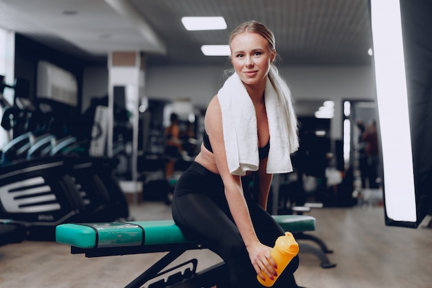 Giovane donna sportiva con un drink in una palestra dopo l'allenamento