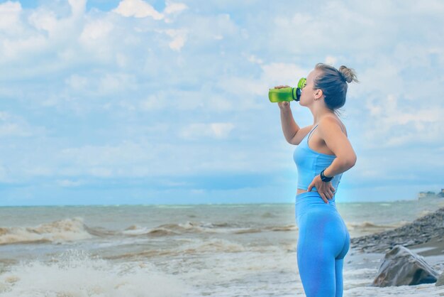 Giovane donna sportiva durante il fitness all'aperto acqua potabile