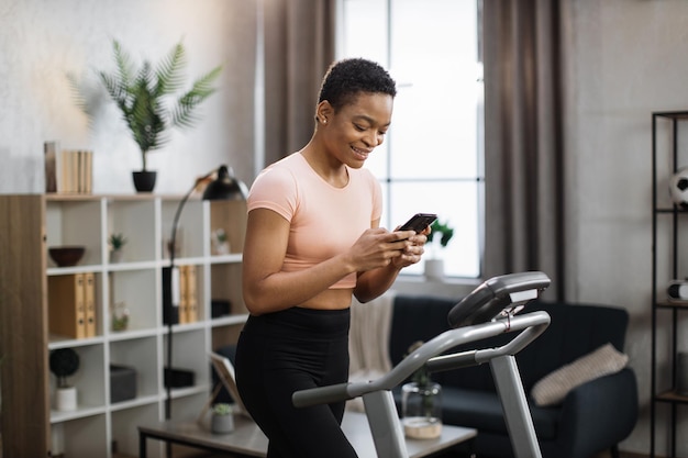 Giovane donna sportiva in buona salute che utilizza il telefono alla ricerca di lezioni di fitness online mentre si allena
