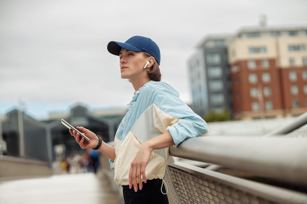 Giovane donna sportiva in buona salute che utilizza il telefono cellulare durante il riposo dopo il jogging