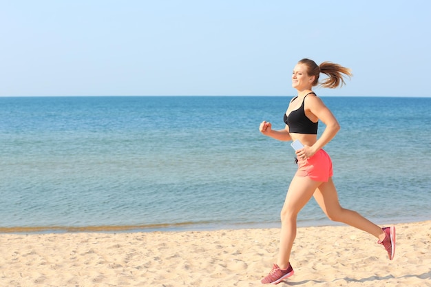 Giovane donna sportiva in esecuzione sulla spiaggia del mare