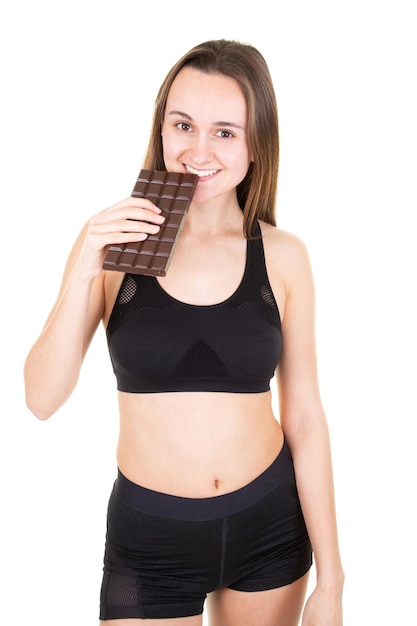 Giovane donna sportiva in studio che mangia barretta di cioccolato