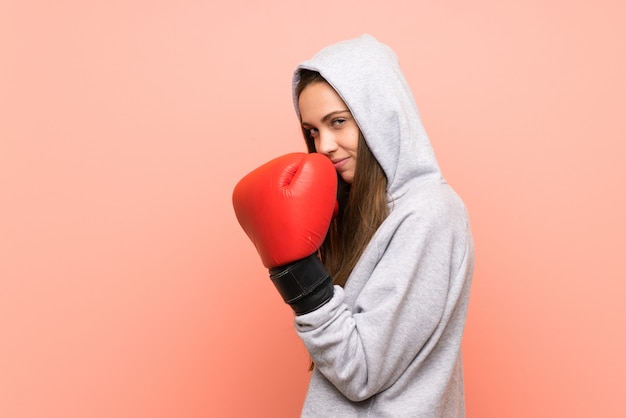 Giovane donna sportiva sopra la parete rosa isolata con guantoni da boxe