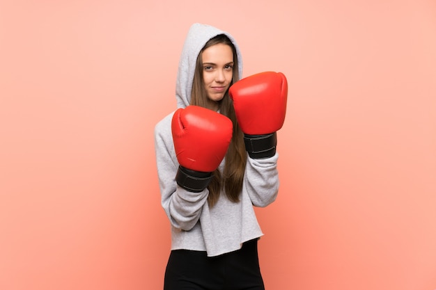 Giovane donna sportiva sopra la parete rosa isolata con guantoni da boxe