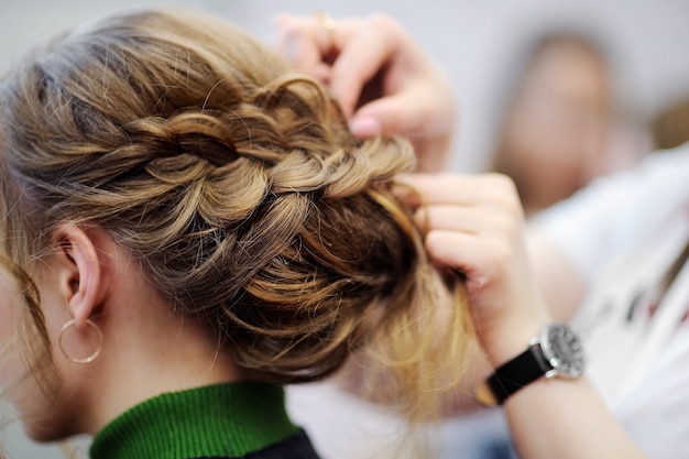 Giovane donna / sposa farsi i capelli prima del matrimonio o della festa