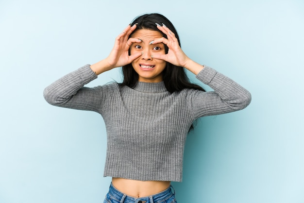 Giovane donna su blu tenendo gli occhi aperti per trovare un'opportunità di successo.