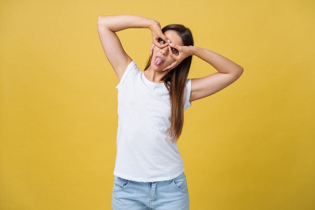 Giovane donna su sfondo giallo faccia felice sorridente facendo segno ok o vetro