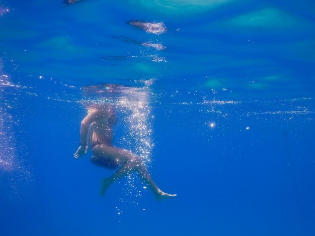 Giovane donna su un sedile con bolle in acqua blu