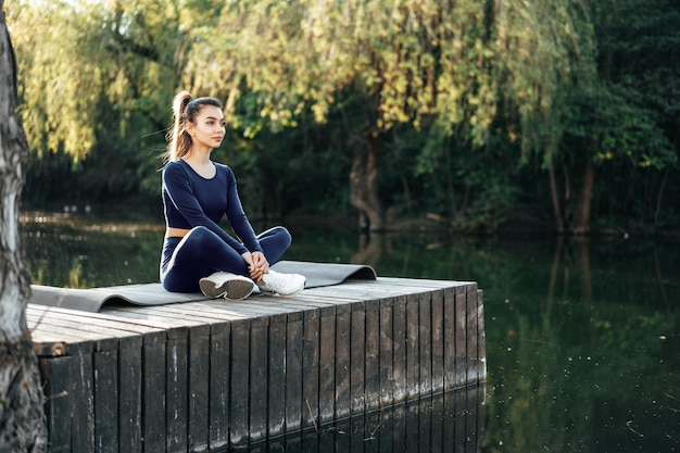 Giovane donna su una stuoia di yoga che si rilassa all'aperto