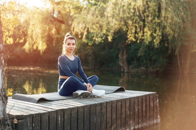 Giovane donna su una stuoia di yoga che si rilassa all'aperto