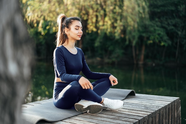 Giovane donna su una stuoia di yoga che si rilassa all'aperto