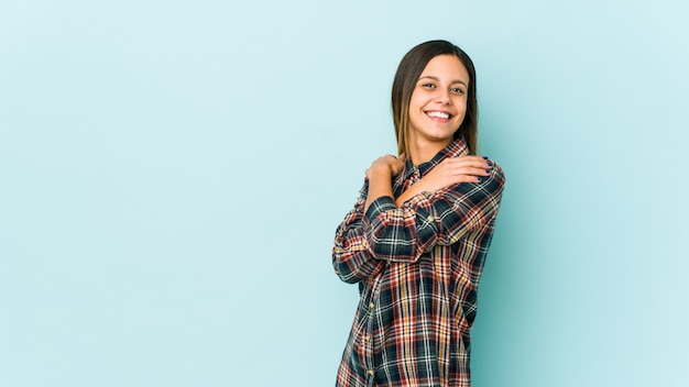 Giovane donna sugli abbracci blu della parete, sorridente spensierato e felice.