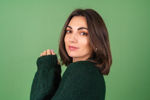 Giovane donna sul verde in un accogliente maglione lavorato a maglia carino sorridente