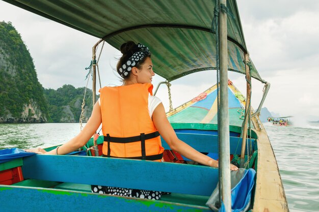 Giovane donna sulla barca della coda lunga durante le sue vacanze in Tailandia